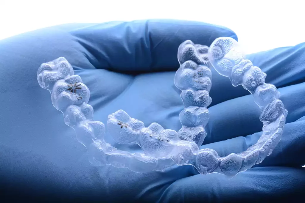 Orthodontics: A person holding clear braces.